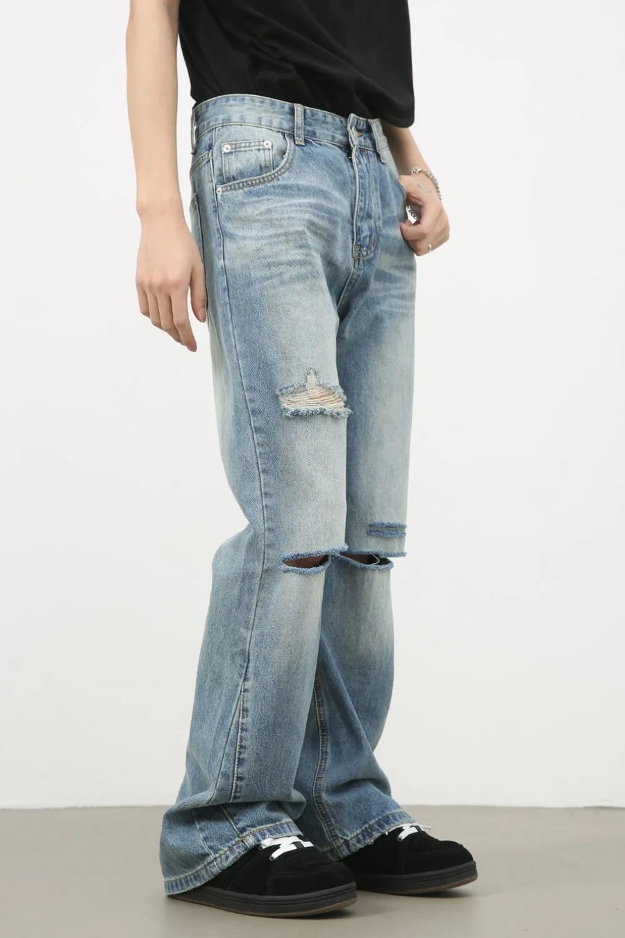 Distressed flare-leg denim jeans in medium wash with ripped knees and frayed hem.