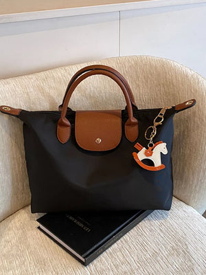 Black nylon tote bag with brown leather accents and a rocking horse charm