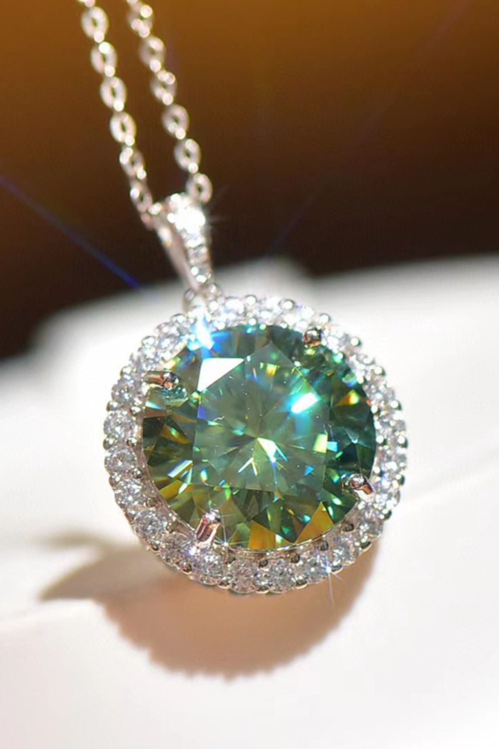 Emerald cut halo moissanite necklace in platinum with a green center stone and diamond accent halo.