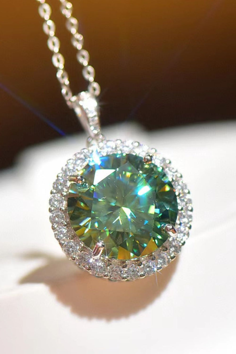 Emerald cut halo moissanite necklace in platinum with a green center stone and diamond accent halo.