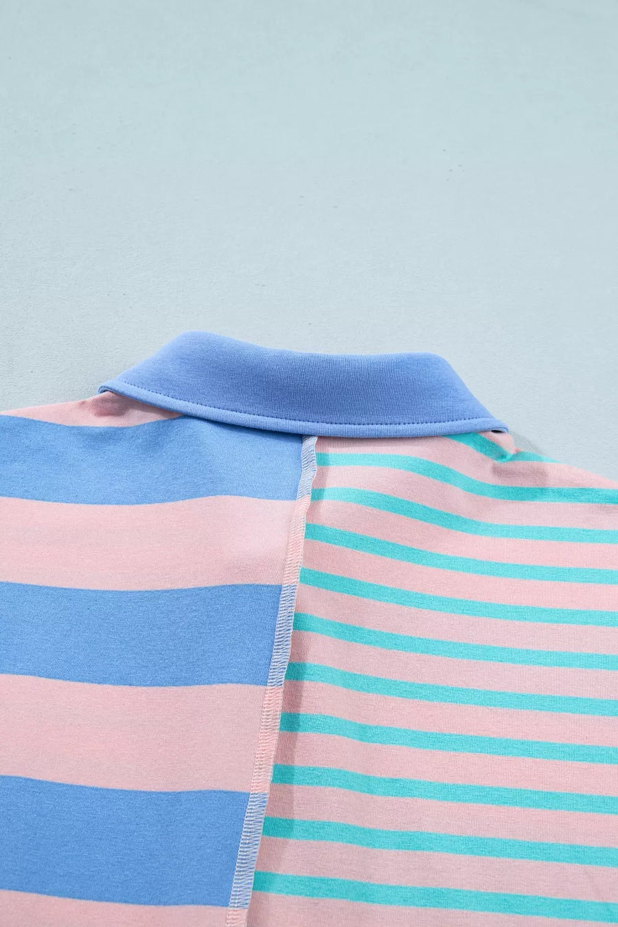 Striped polo shirt with blue collar and pink, blue, and teal stripes
