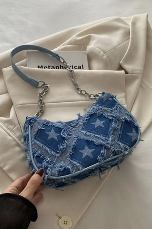 Denim shoulder bag with starburst pattern and distressed details.