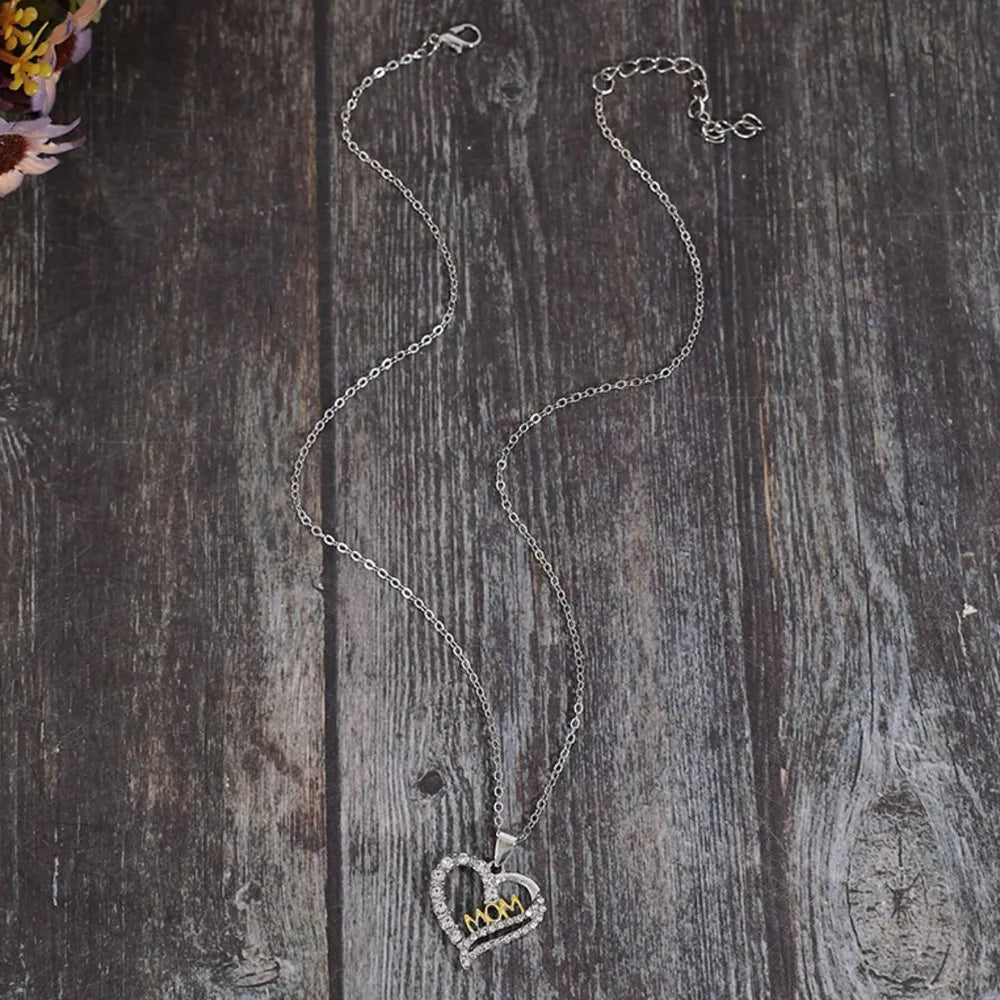 Silver heart necklace with crystal accents and gold "MOM" cutout, on a delicate chain.
