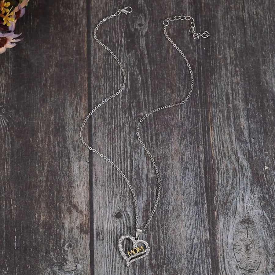 Silver heart necklace with crystal accents and gold "MOM" cutout, on a delicate chain.