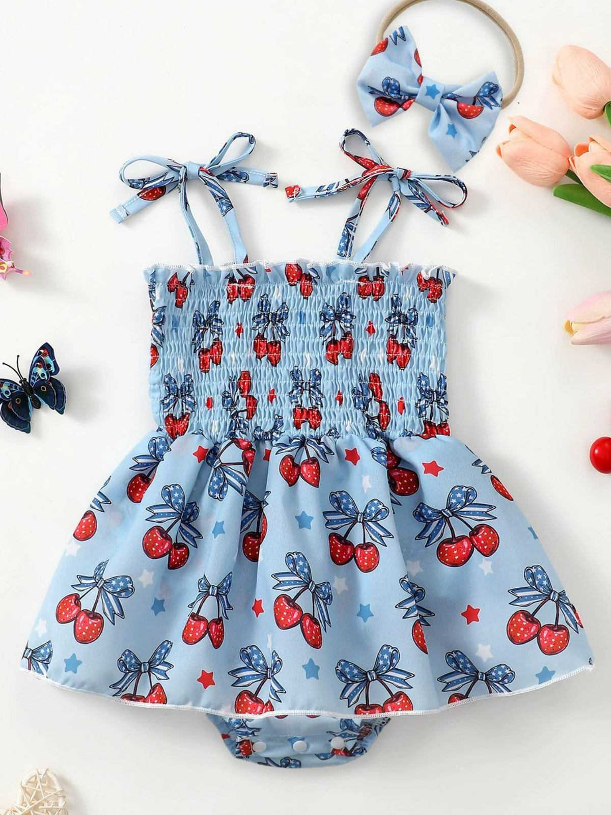 Baby bodysuit dress set with cherry print, smocked bodice, tie straps, and matching headband.