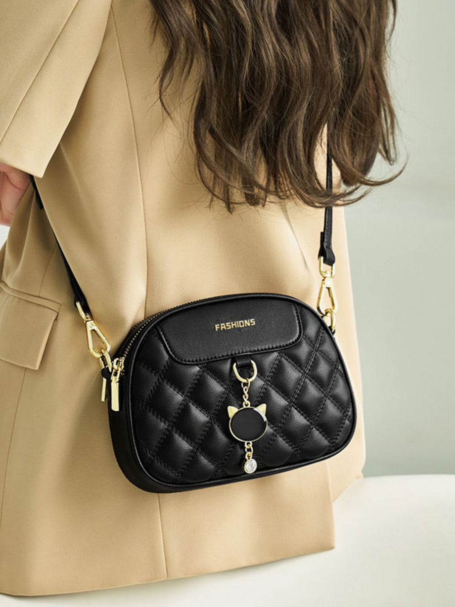 Black quilted PU leather crossbody bag with cat charm and gold hardware.