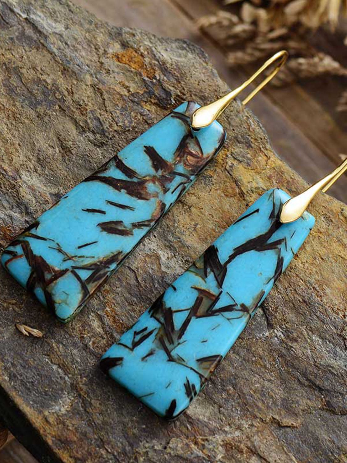 Geometric stone drop earrings in sky blue with dark brown inclusions and gold hooks.