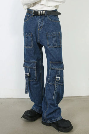 Medium wash denim cargo pants with buckle strap pockets and wide legs.