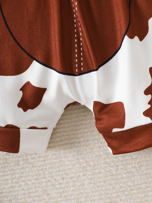 Baby bodysuit and shorts set with brown and white cow print, featuring contrast stitching detail.