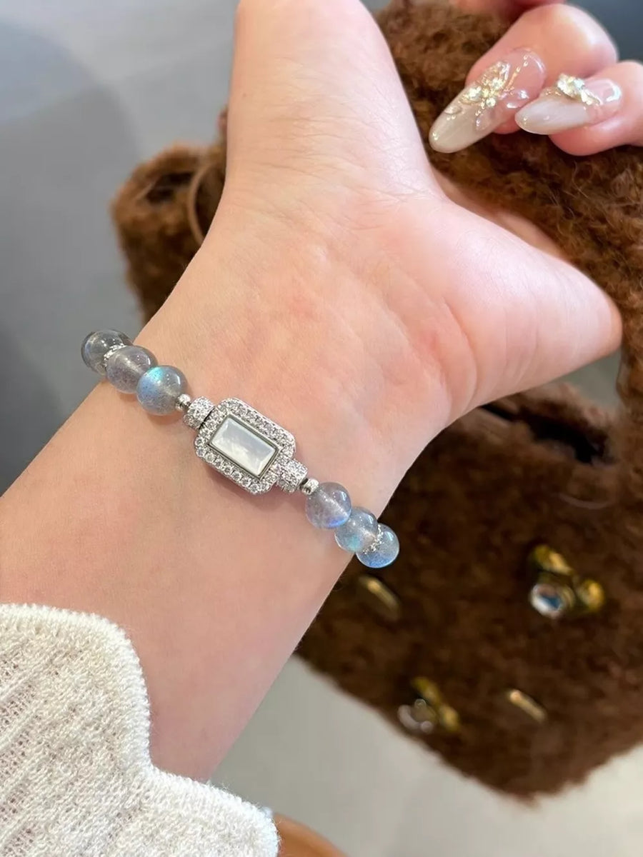 Iridescent moonstone beaded bracelet with rectangular crystal charm and silver accents.