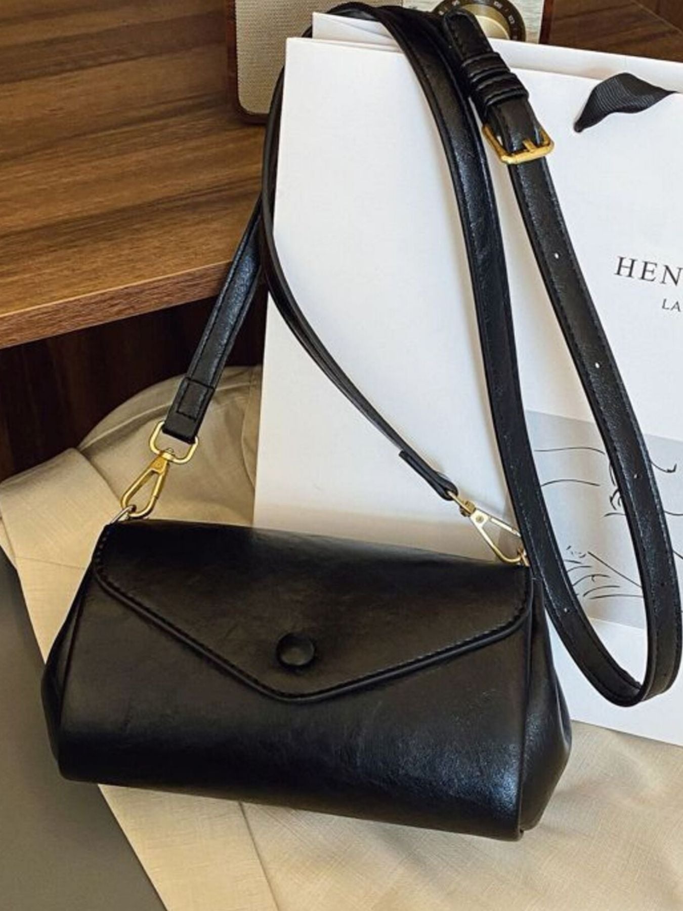 Black mini pu leather flap crossbody bag with gold hardware and adjustable strap.