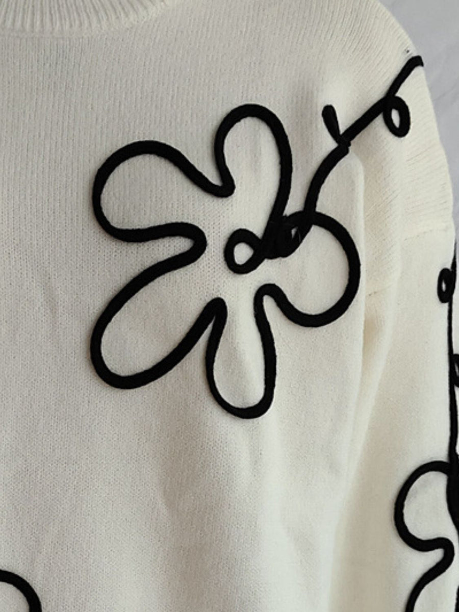 Beige knit sweater with black floral outline embroidery, crew neck, long sleeves.
