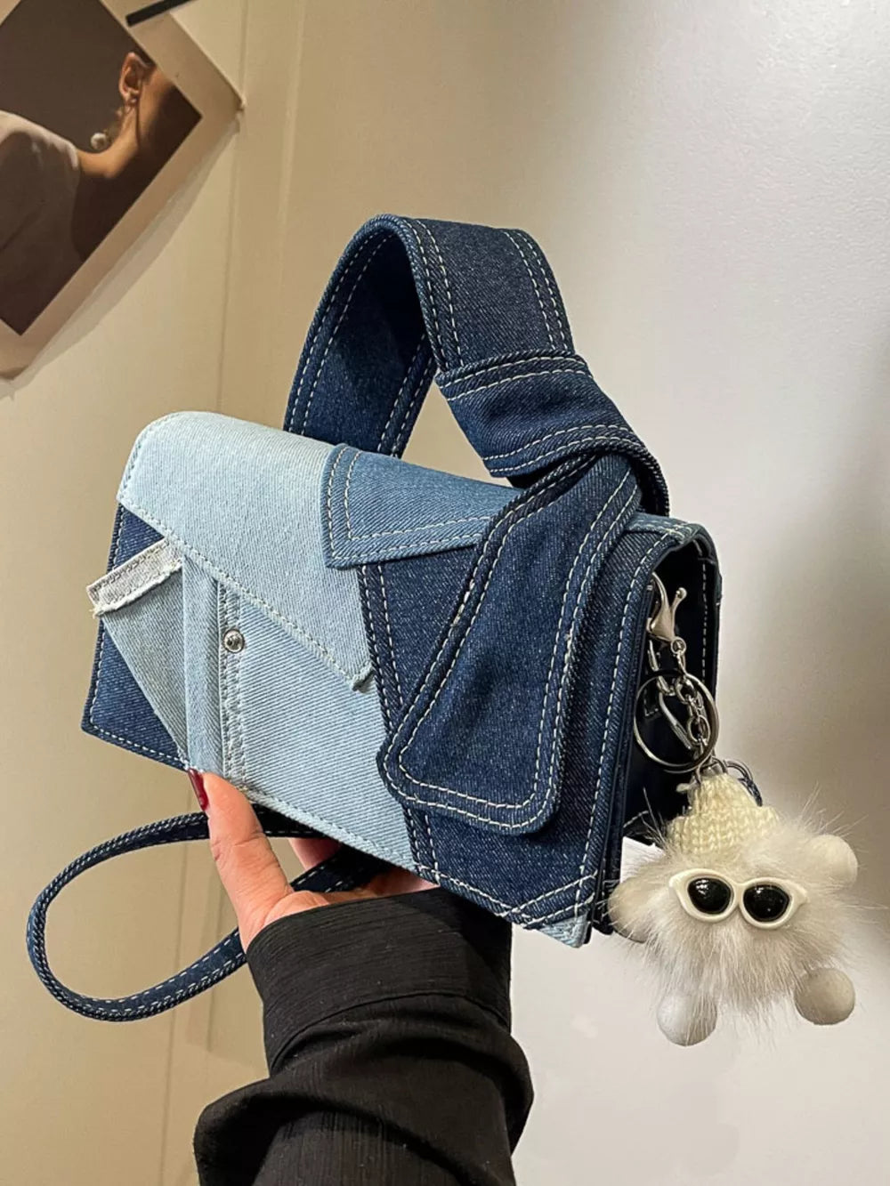 Artisanal mini denim crossbody bag in patchwork light and dark blue denim with a fuzzy keychain charm.