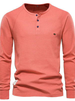 Burnt Coral waffle knit henley top with raglan sleeves and button placket.