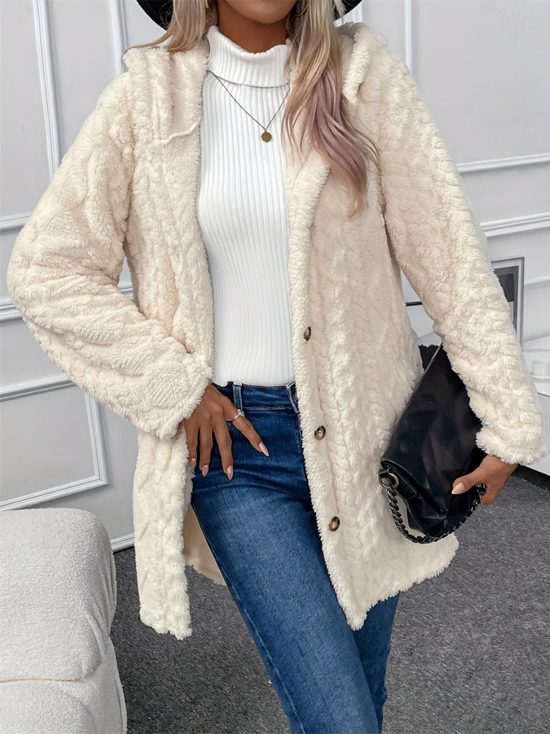 Cream textured teddy bear coat with hood and button closure, styled with jeans.