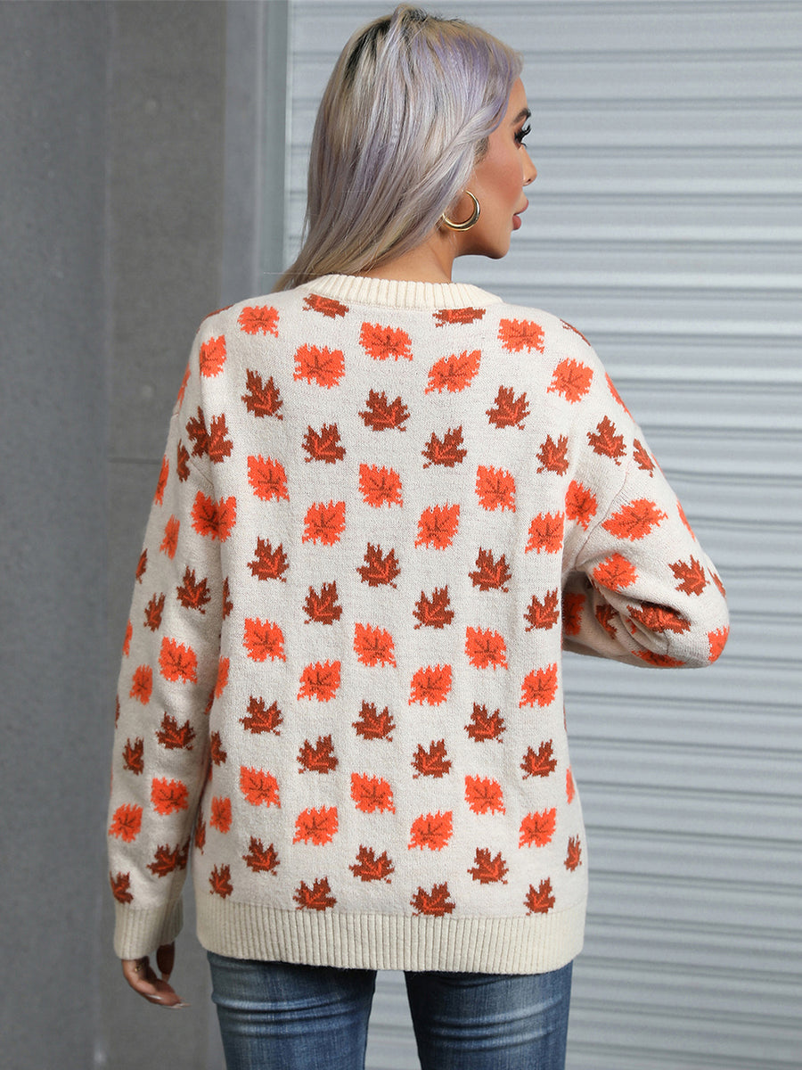 Cream knit crewneck sweater with allover orange and brown autumn leaf pattern.