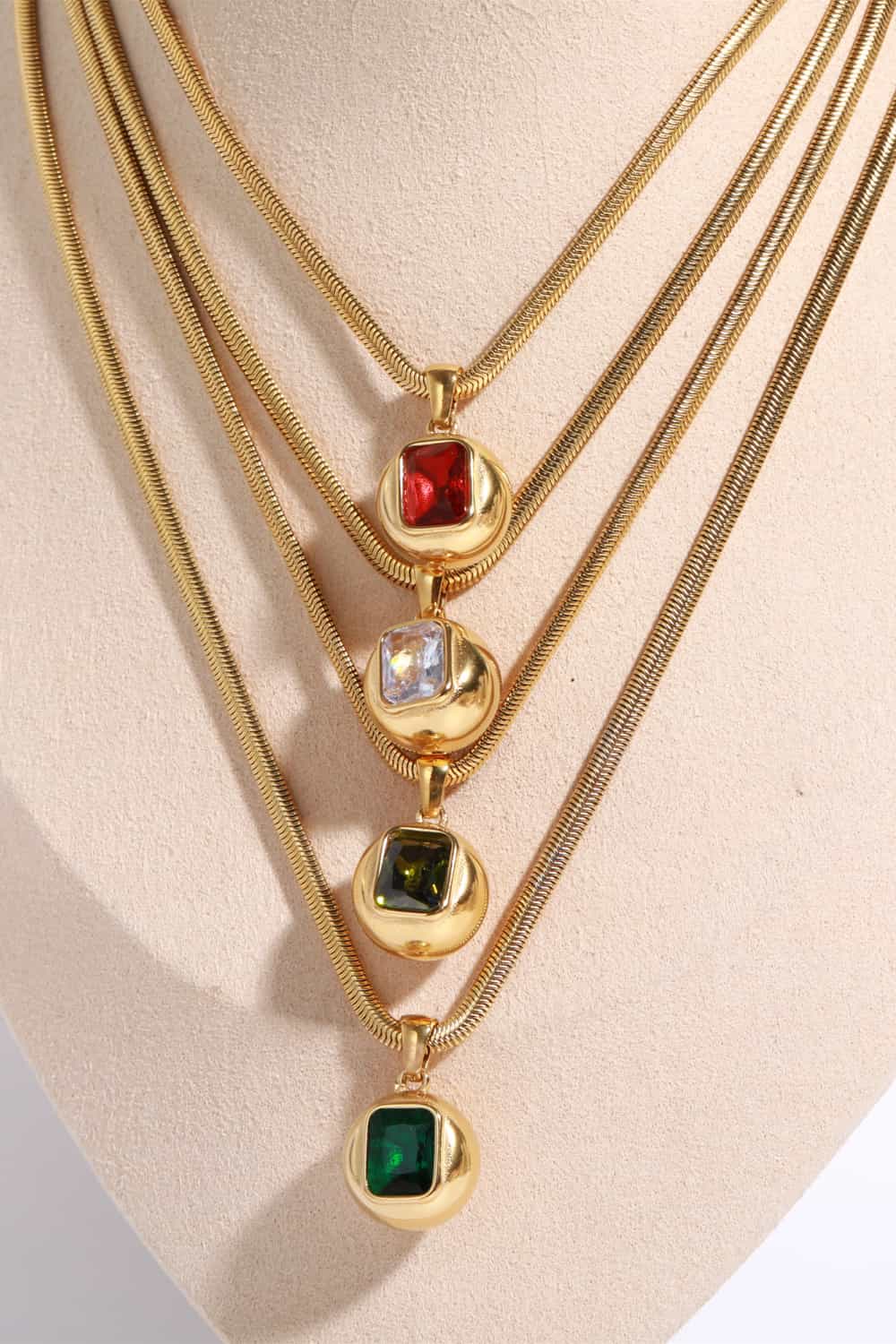 Sculpted orb & square stone necklace with deep red, transparent, and dark green stones on gold snake chains.