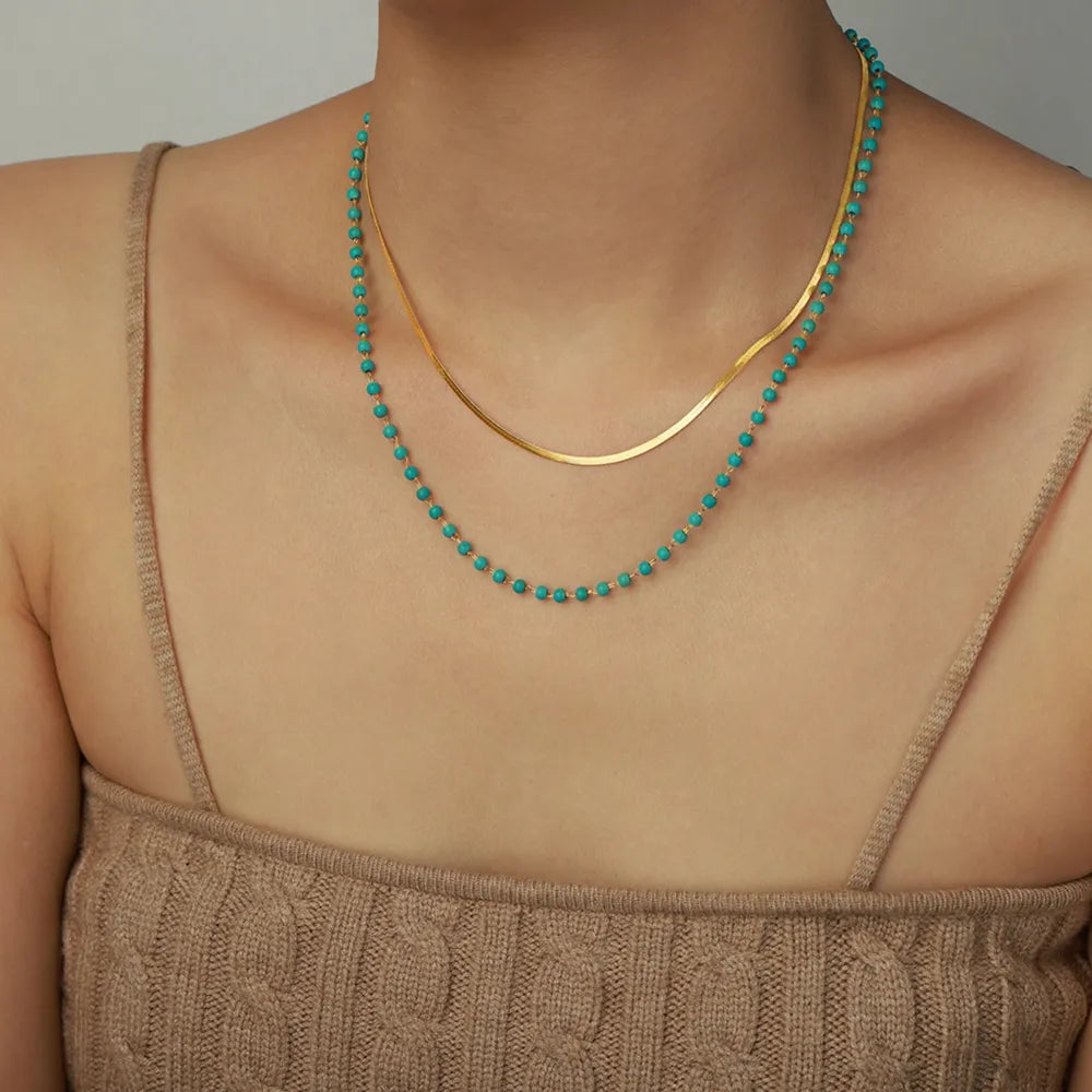 Gold layered necklace with turquoise beads and a flat snake chain