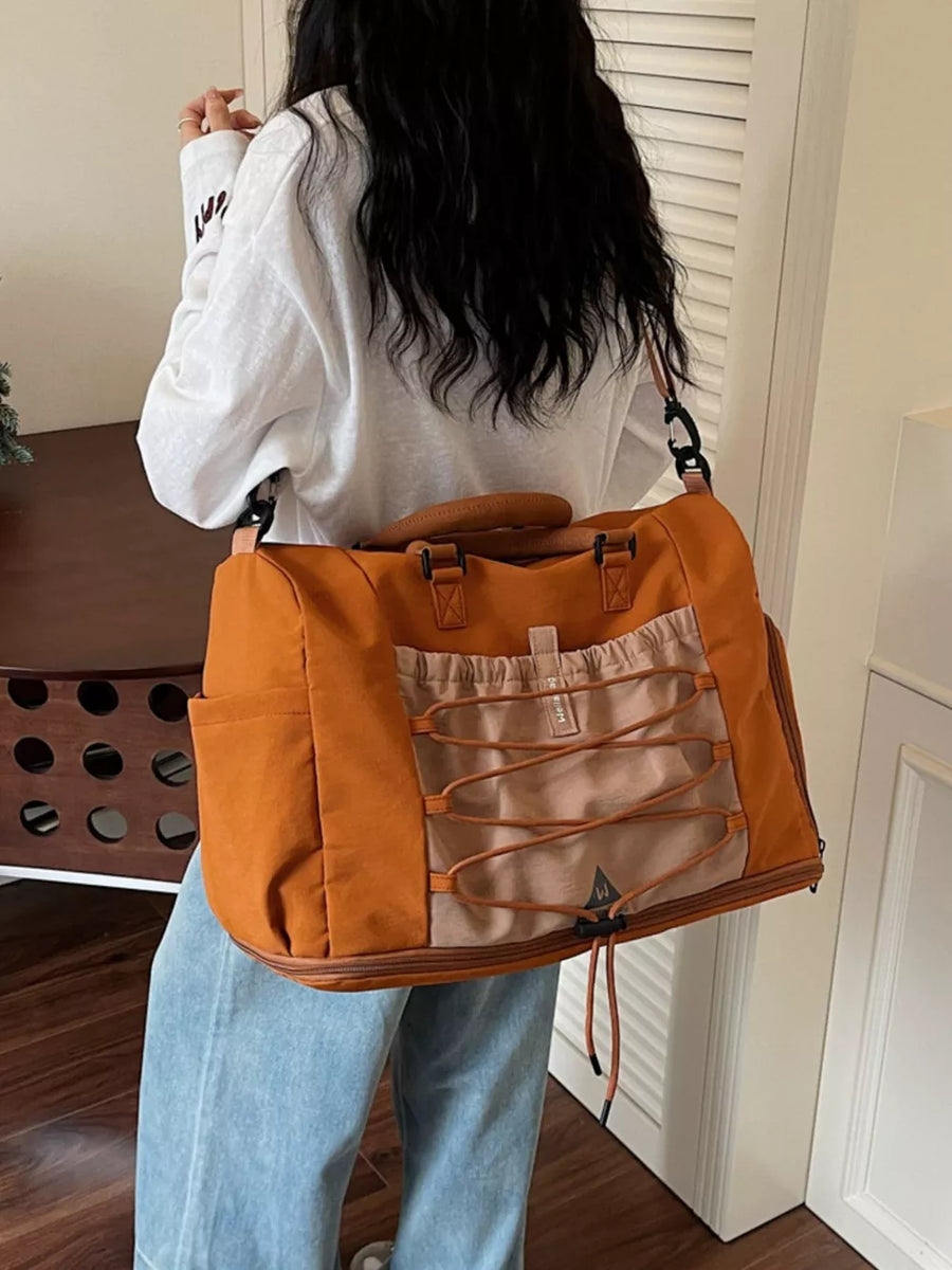 Large orange nylon duffel bag with bungee cord detail and tan accents