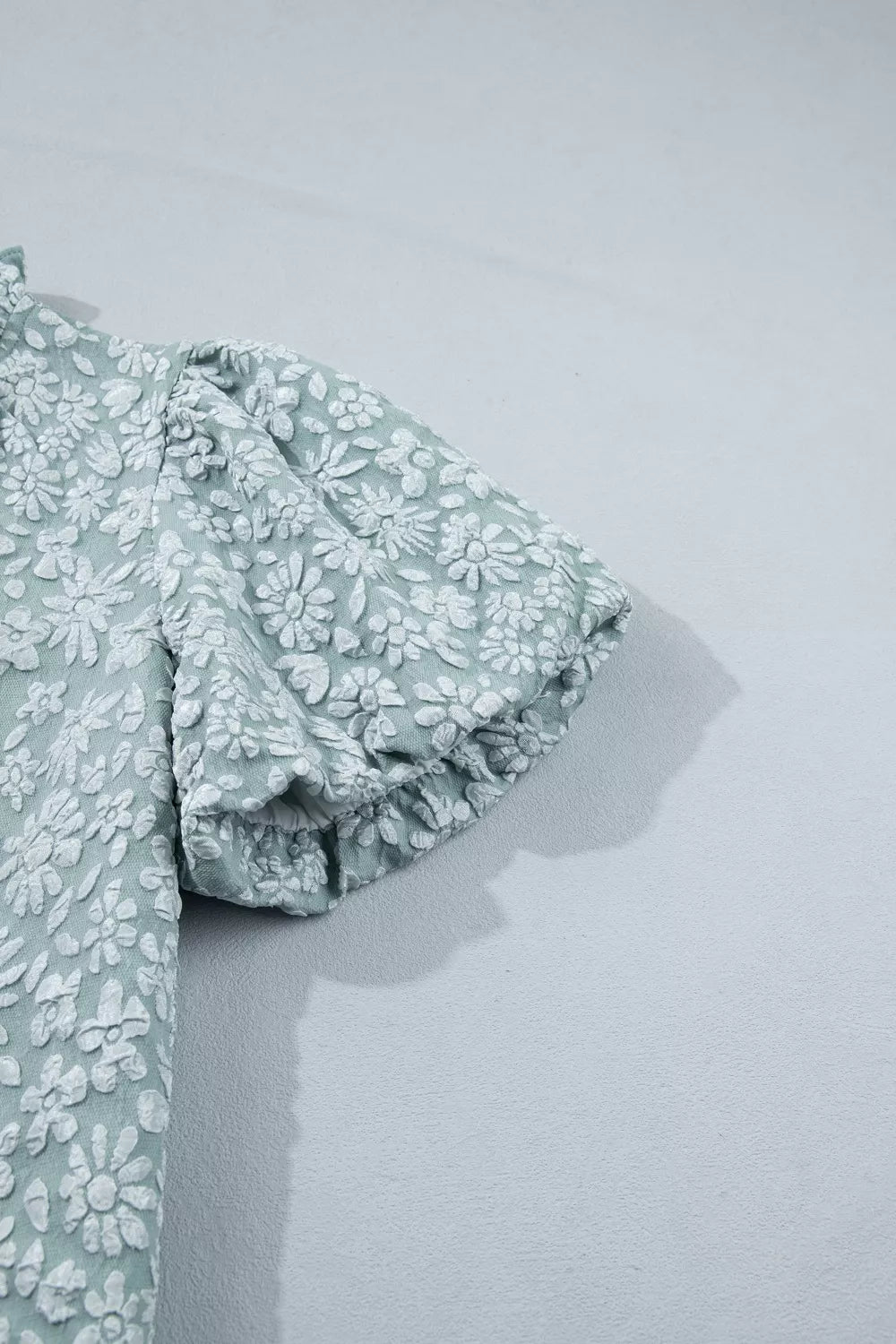 Embroidered puff sleeve floral shirt in light green polyester with textured white floral pattern.