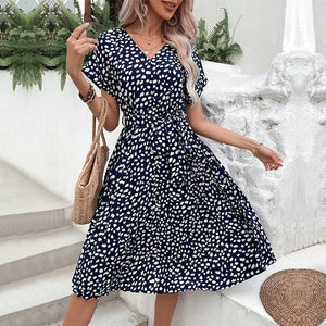 Dark blue midi dress with white dots, V-neck, short sleeves, belted waist, and A-line skirt.