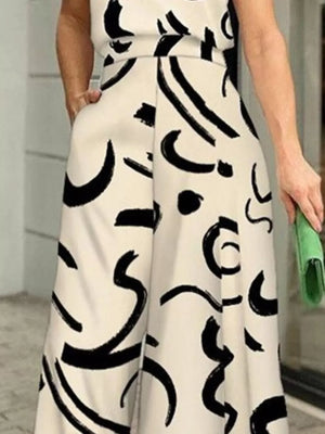 White halter neck romper with abstract black print and wide legs.