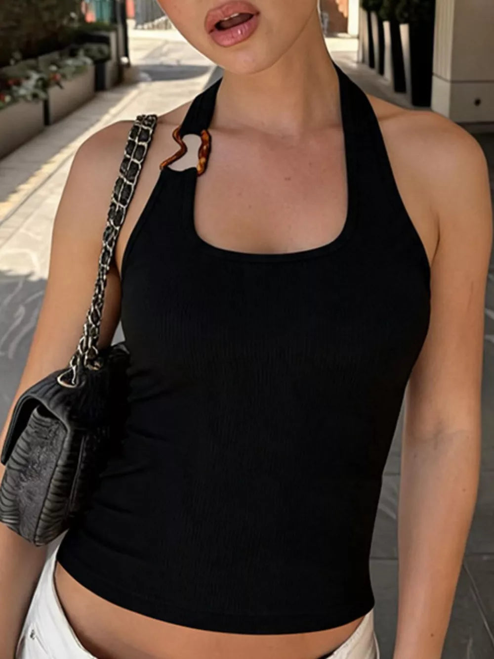 Black ribbed halter tank top with scoop neck and decorative tortoise ring detail.