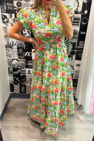 Vibrant floral maxi dress with ruffled neckline, smocked waist, and tiered skirt.