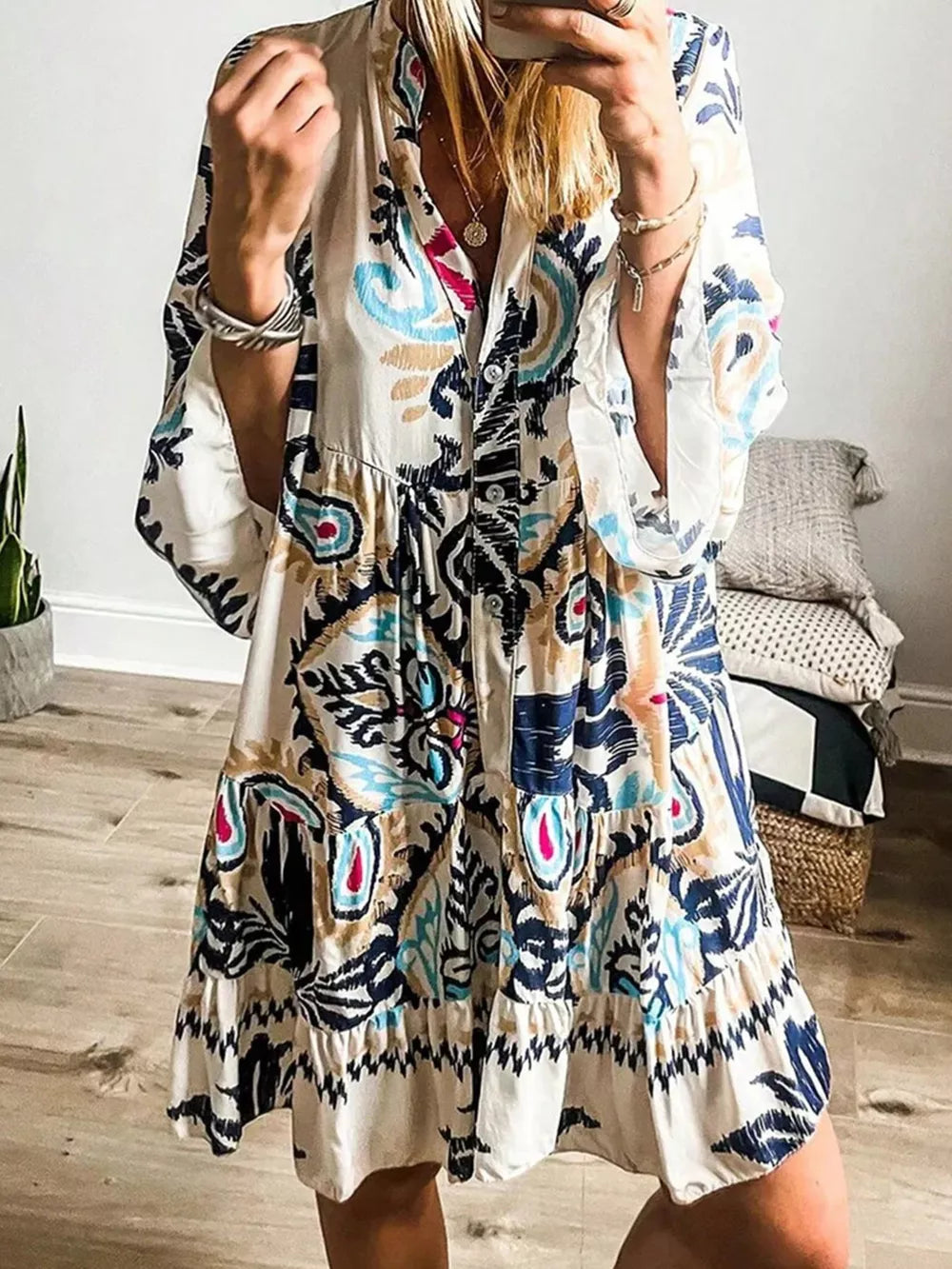 Vibrant tiered mini dress with abstract print, button detail, collared neckline and flared sleeves.