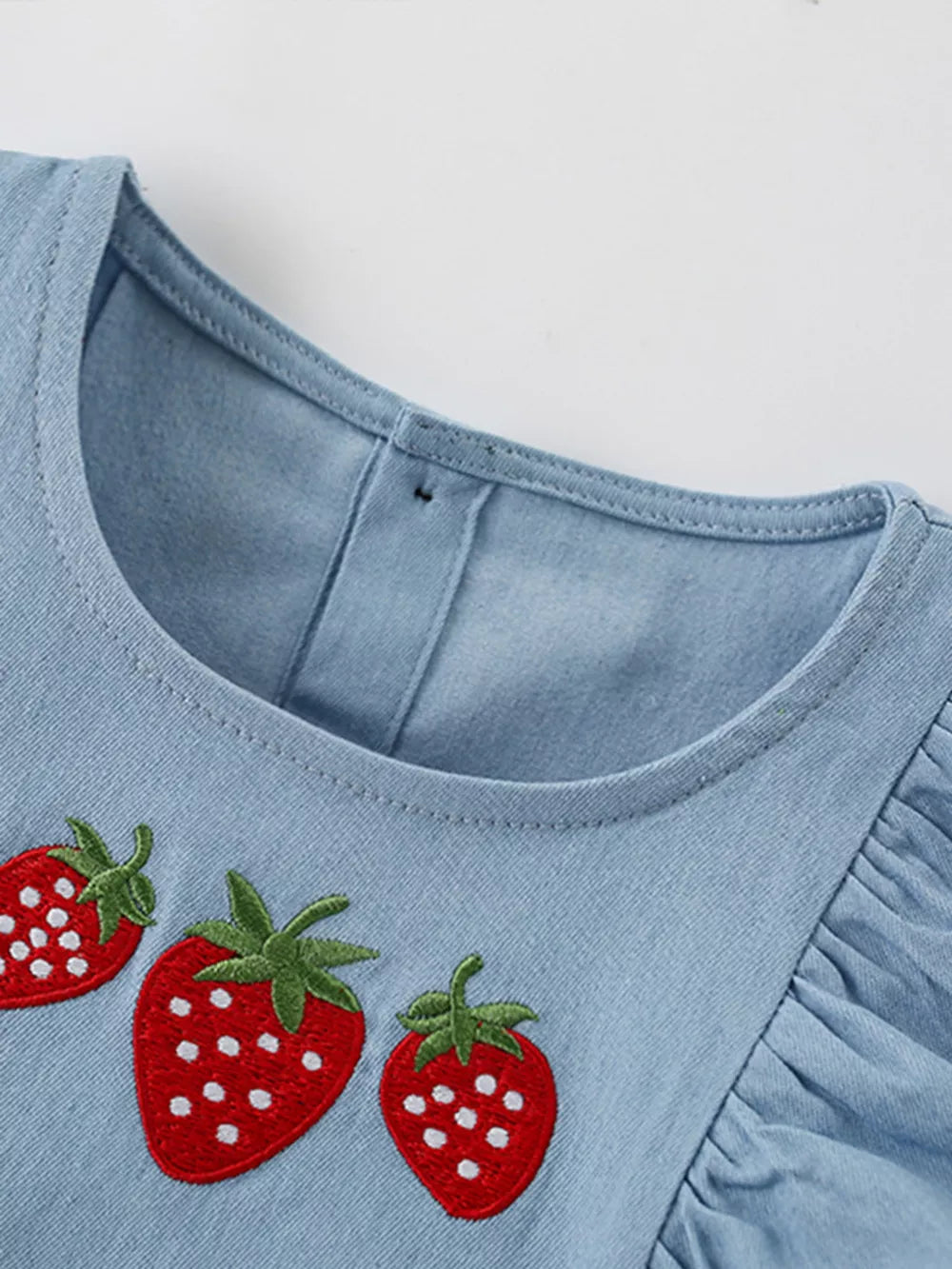 Baby denim dress with strawberry embroidery and ruffled sleeves.