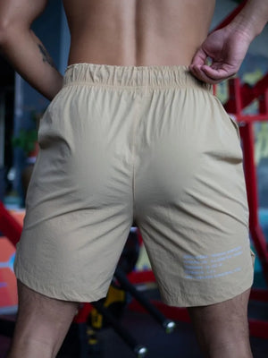 Khaki athletic shorts with drawstring waist and subtle text detail on leg
