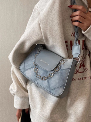 Blue textured leather shoulder bag with decorative chain strap and braided strap detail.