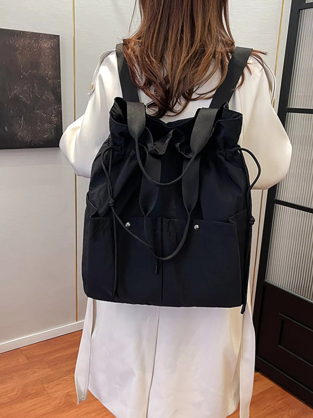 Black drawstring backpack with ruched top and exterior pockets.