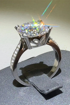 Silver moissanite engagement ring with pavé band and round center stone.