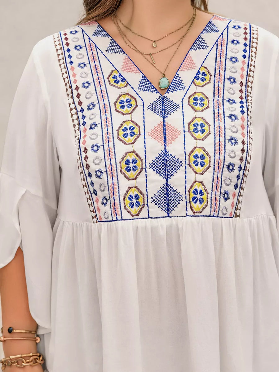 White plus size shirt with vibrant geometric embroidery and bell sleeves.