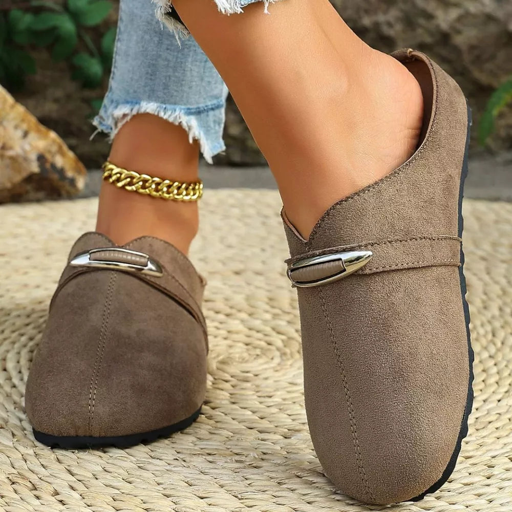 Brown slip-on flats with decorative buckle detail and round toe.