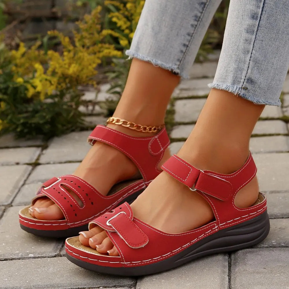 Red perforated detail velcro wedge sandals with adjustable straps and white stitching.