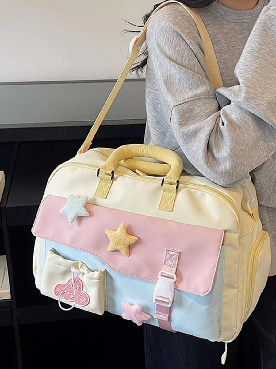 Chic color block travel bag with star embellishments and pastel pink, blue, and yellow panels.
