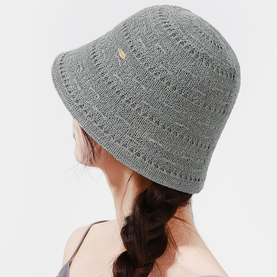 Gray knitted bucket hat with openwork pattern and small gold accent detail.
