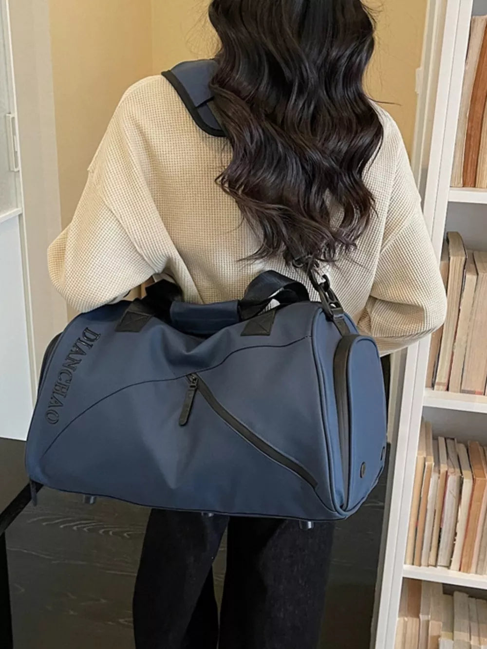 Blue Oxford travel bag with padded strap and zippered compartment.
