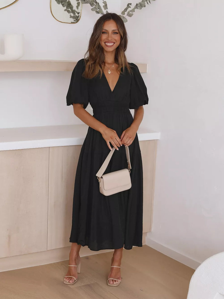 Black midi dress with puff sleeves and V-neck, cinched waist, flowing skirt.