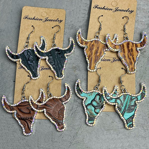 Crystal-trimmed bull skull earrings in black, brown, caramel, and teal with embossed detail.