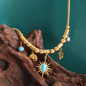 Gold celestial charm necklace with sunburst, tree of life, and turquoise charms