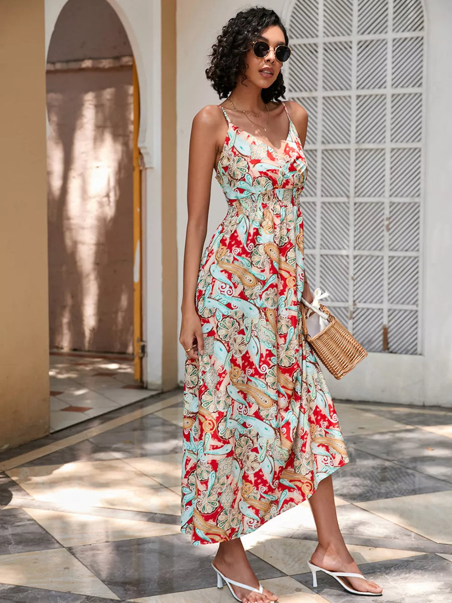 Chic floral midi dress with spaghetti straps and a cinched waist, featuring a red, blue, and gold paisley print.