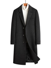 Men's dark gray longline wool buttoned overcoat with classic lapels and a white turtleneck.