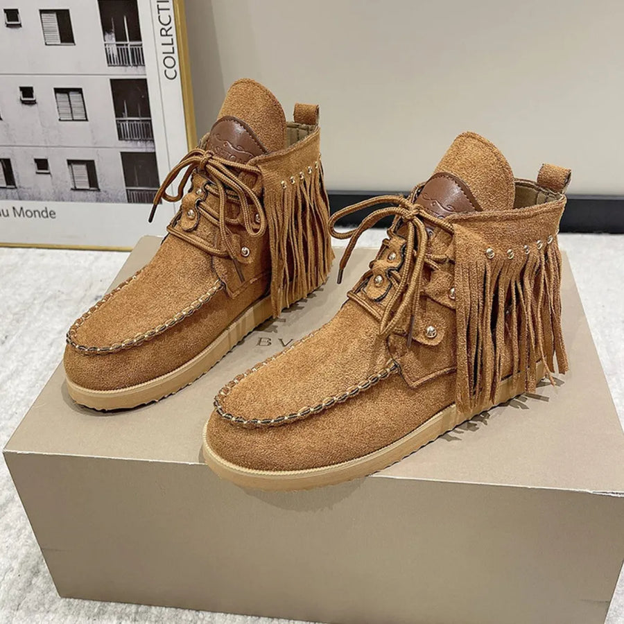 Brown suede moc-toe ankle boots with fringe and stud details.