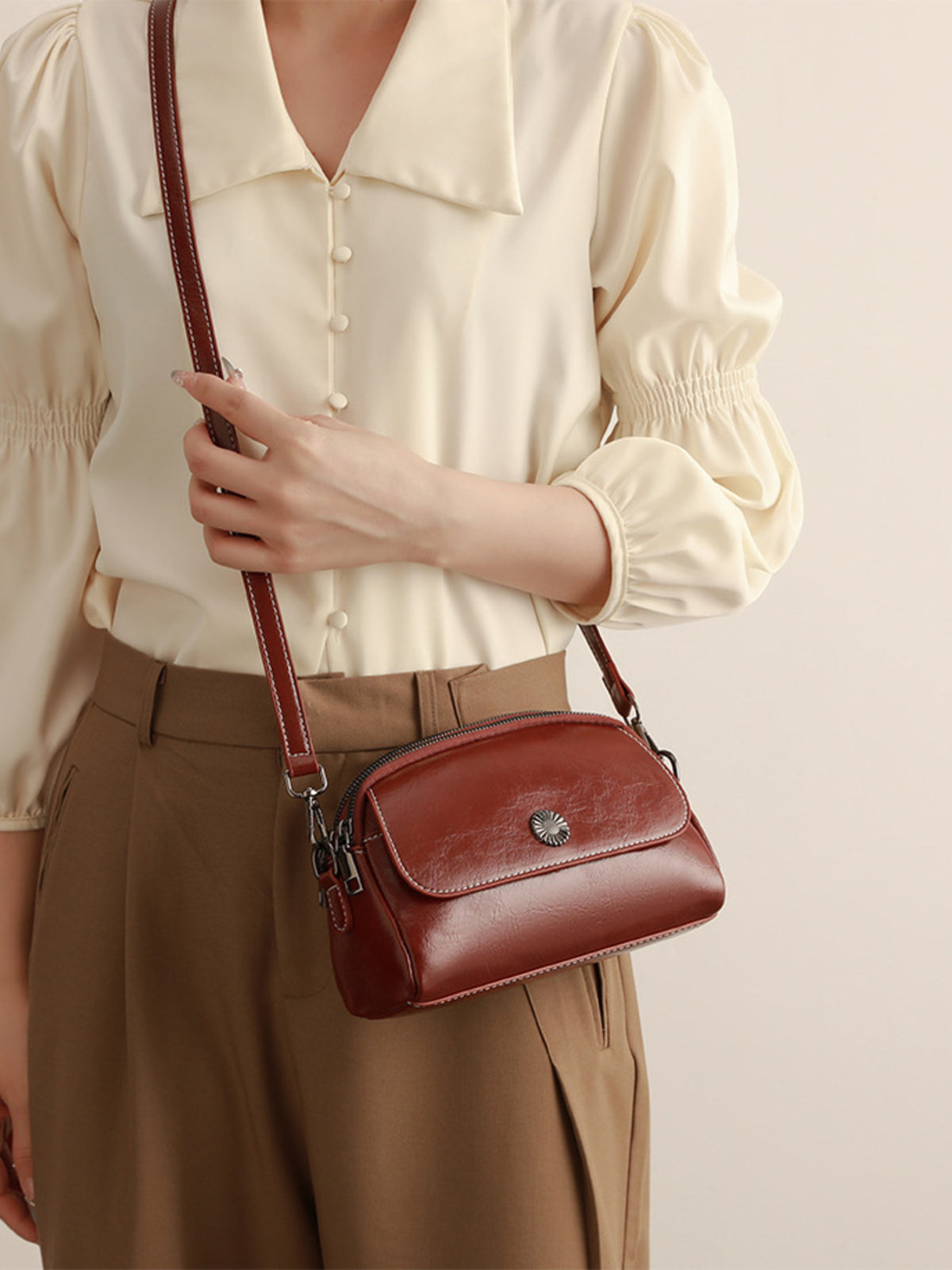 crossbody bag in cognac featuring metal emblem and structured fit