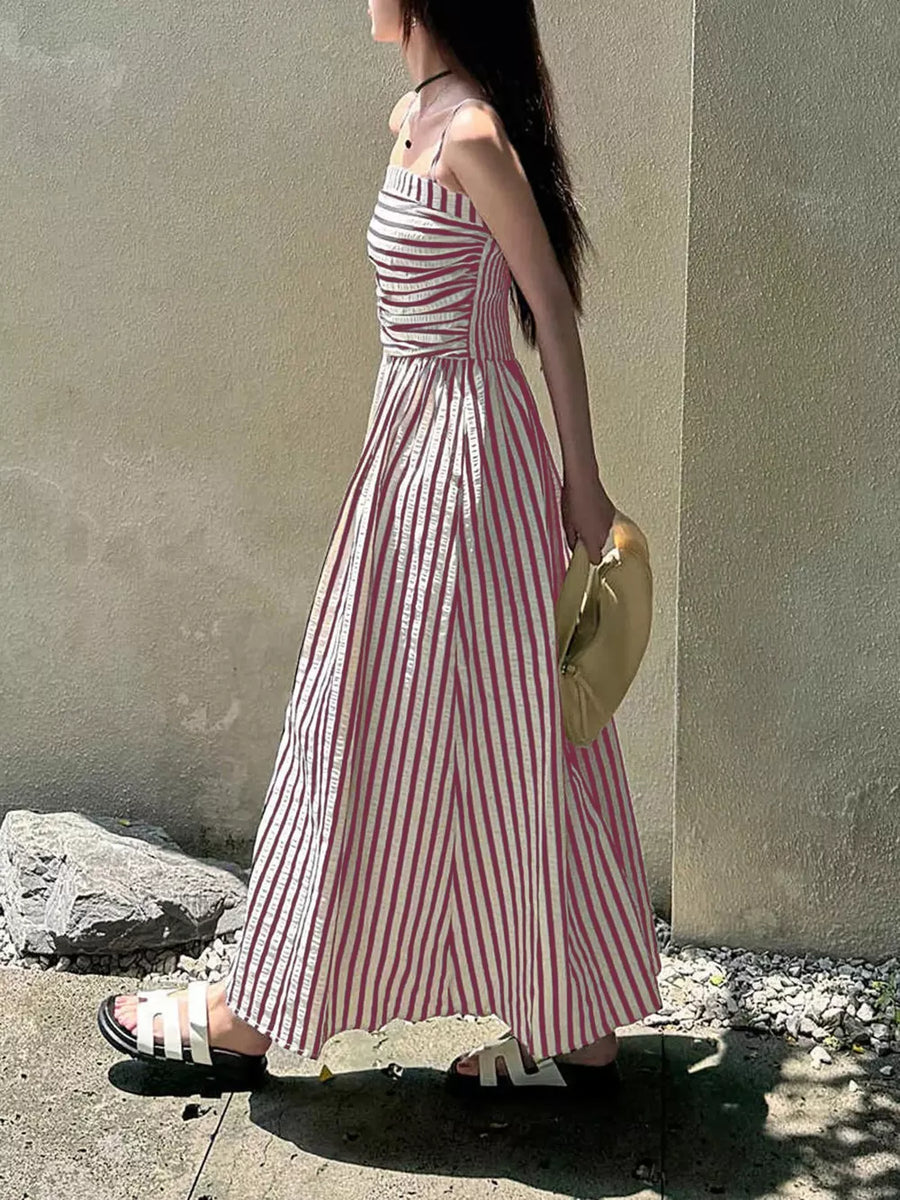 Pink striped maxi dress with slit and spaghetti straps, worn with white sandals.