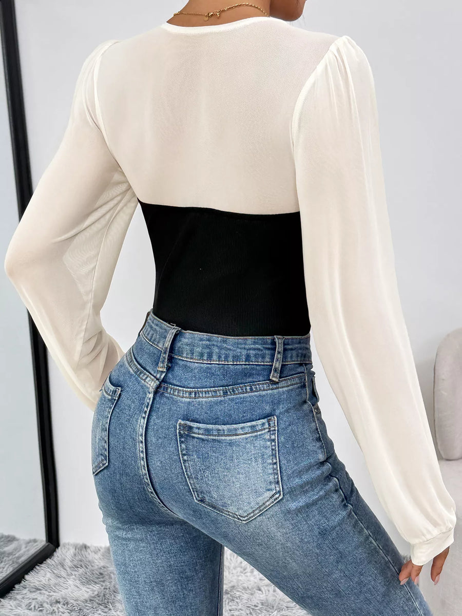 Black and white long-sleeve mesh bodysuit with ribbed black panel, styled with jeans.