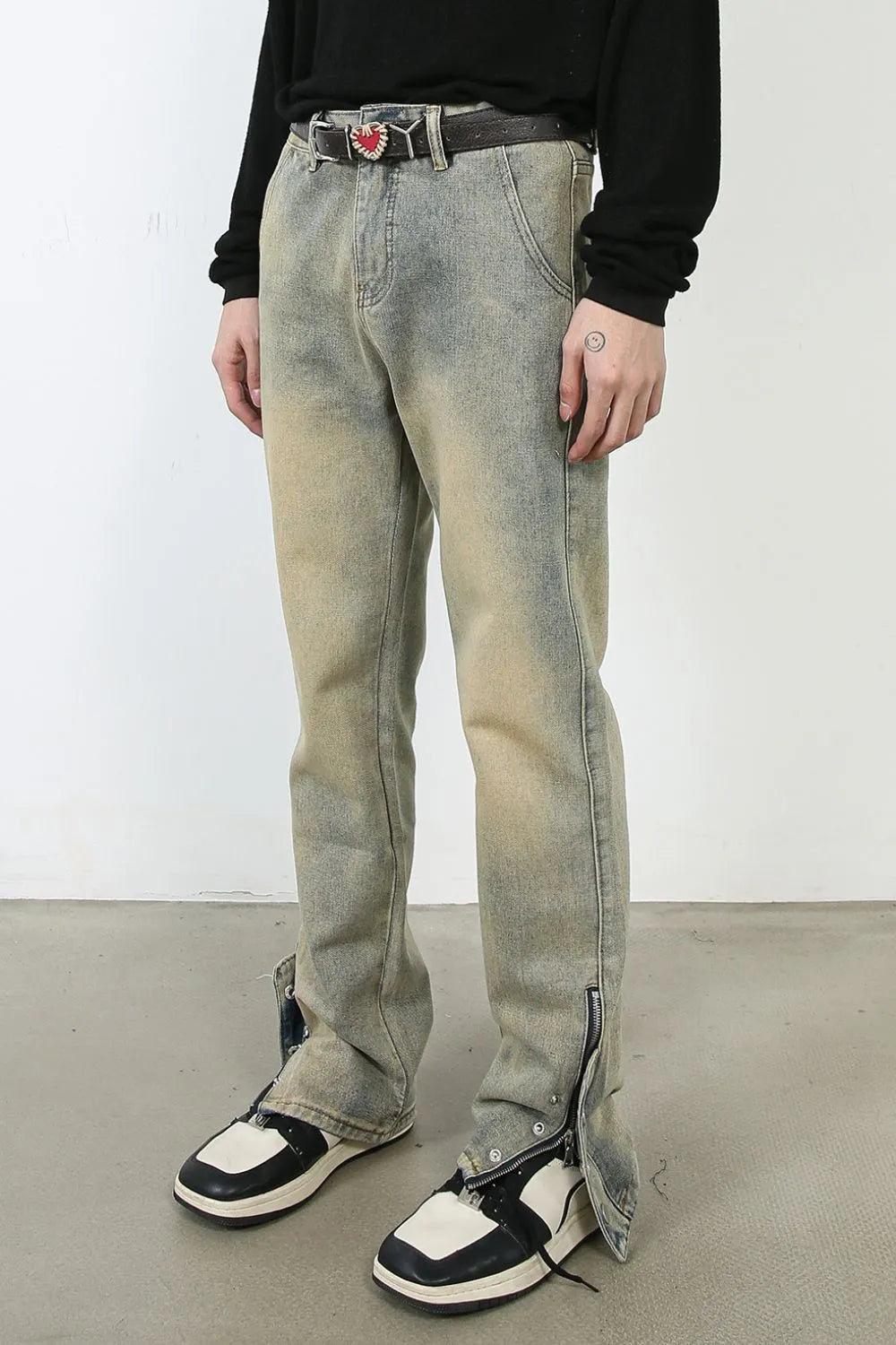 Distressed denim jeans in light wash with split hem and zipper details.